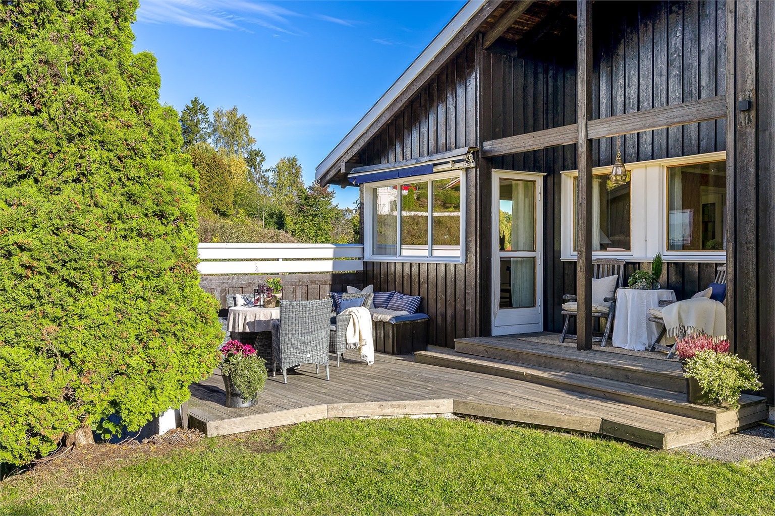 Terrasse utenfor stue og kjøkken. Et hyggelig samlingsområde utendørs på en fin sommerdag. 