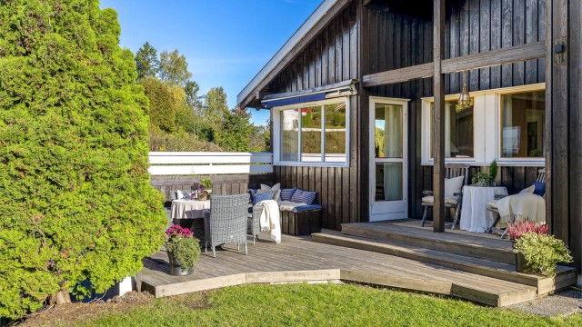 Terrasse utenfor stue og kjøkken. Et hyggelig samlingsområde utendørs på en fin sommerdag.