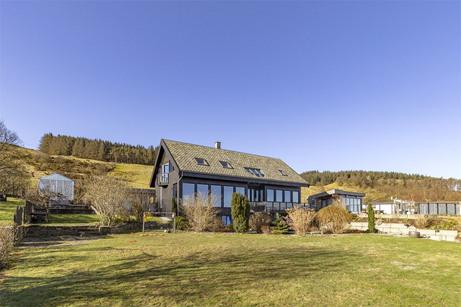 Boligen er plassert på en svakt skrånende tomt i to nivåer, noe som gir en dynamisk hage.