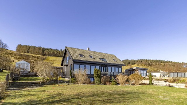 Boligen er plassert på en svakt skrånende tomt i to nivåer, noe som gir en dynamisk hage.