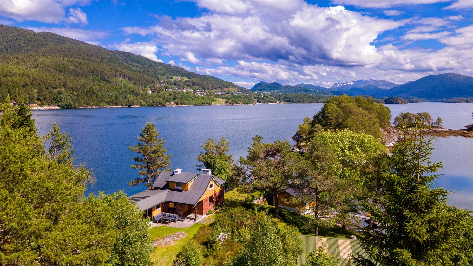 Dronebilde av eiendommen sett fra vest mot øst med boligfeltet i Grindvika på Skodje i bakgrunnen