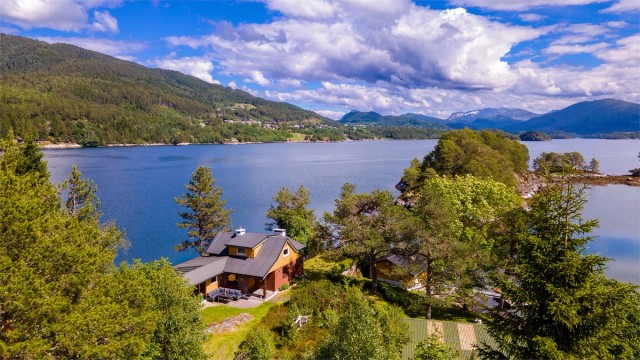 Dronebilde av eiendommen sett fra vest mot øst med boligfeltet i Grindvika på Skodje i bakgrunnen
