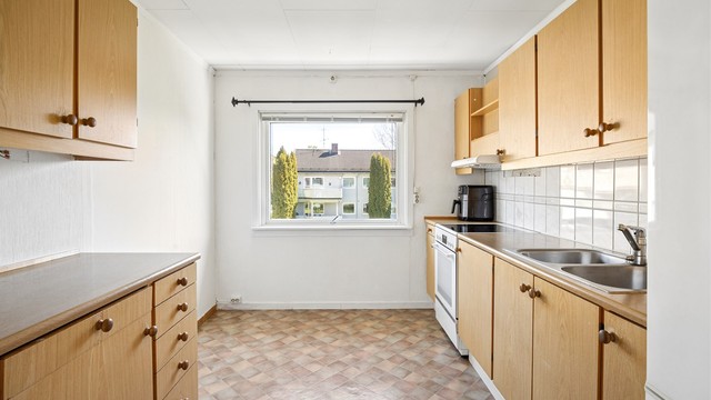 Kjøkkeninnredning med glatte fronter og benkeplate med laminert overflate. Plass til frittstående komfyr og kjøleskap.