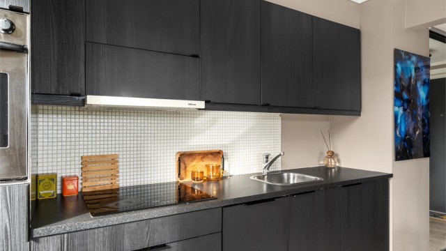 Mosaikkfliser over laminert benkeplate og ventilator plassert i overskap.