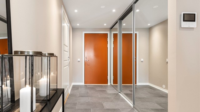 Entréen har flislagt gulv med varme og en romslig skyvedørsgarderobe med speilfronter