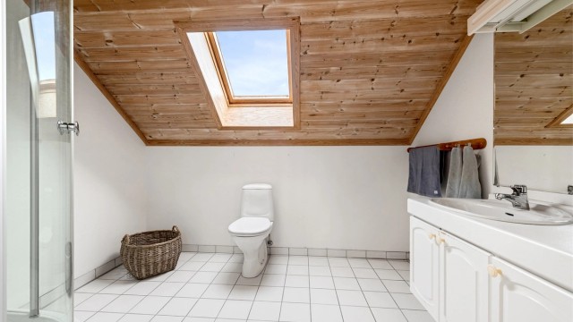 Badet i 2. etasje har profilert hvit baderomsinnredning, toalett og dusjkabinett