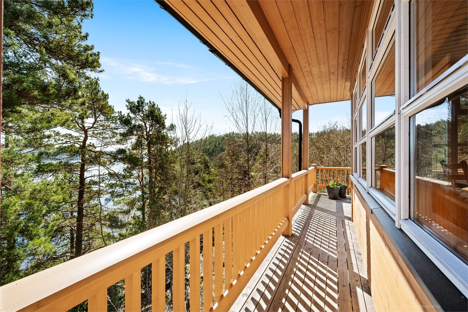 Verandaen/terrassen strekker seg langs store deler av hytta og binder rommene sammen utvendig.