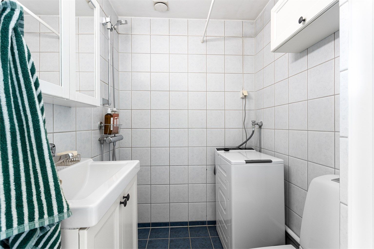 Badet er innredet med servant, speilskap, toalett og dusjhjørne.