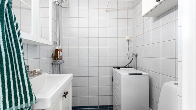 Badet er innredet med servant, speilskap, toalett og dusjhjørne.