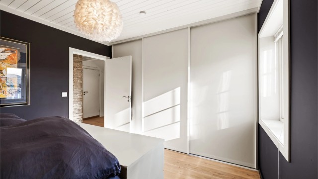 Hovedsoverommet i 2. etasje har en plassbygget skyvedørsgarderobe i hvit og glatt utførelse.
