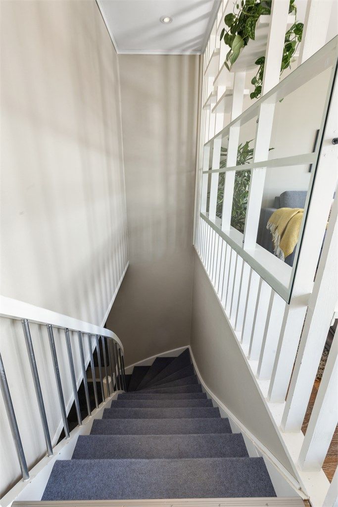 Innvendig trapp i tre med teppe i trinnene forbinder første og andre etasje.