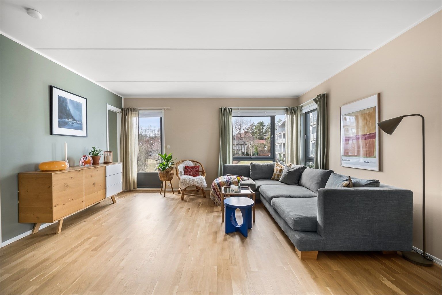 De store vindusflatene gir rikelig med naturlig lys. Leiligheten ligger i første etasje, men er hevet fra bakkenivå.