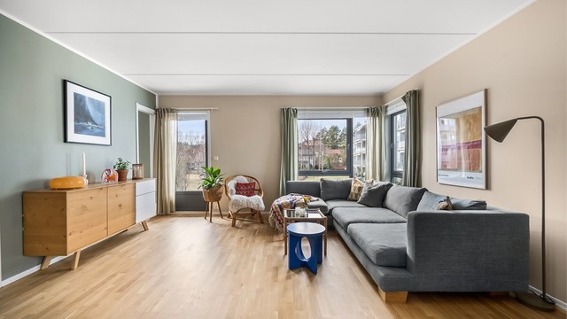 De store vindusflatene gir rikelig med naturlig lys. Leiligheten ligger i første etasje, men er hevet fra bakkenivå.