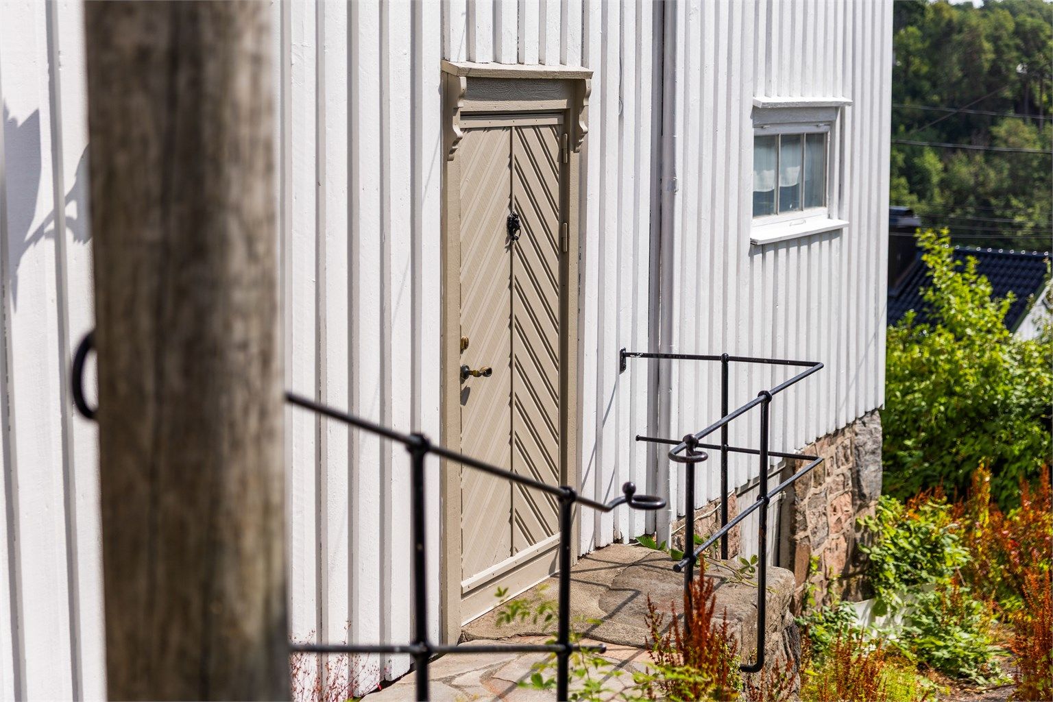 Detalj av fasaden med en sjarmerende, eldre inngangsdør. Det er flere detaljer på huset fra byggeårsperioden, rundt 1800-tallet.
