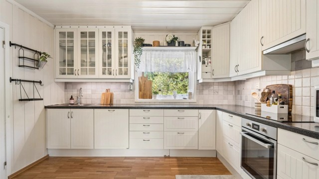 Kjøkkenet har innredning med glatte fronter, laminert benkeplate og integrerte hvitevarer som stekeovn, platetopp og oppvaskmaskin.
