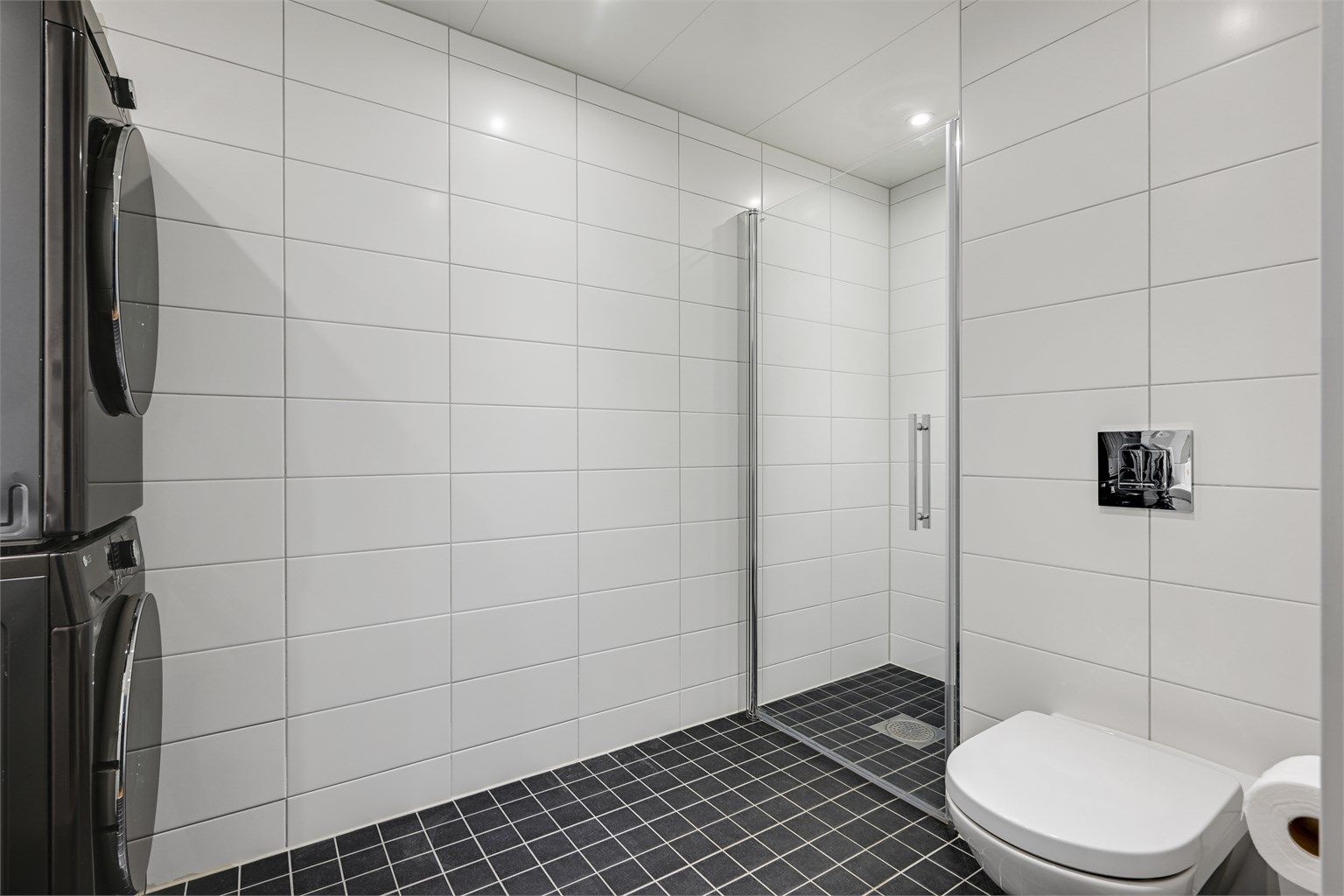 Badet er moderne innredet med heldekkende servant, vegghengt toalett, dusjnisje med glassvegger og opplegg for vaskemaskin.