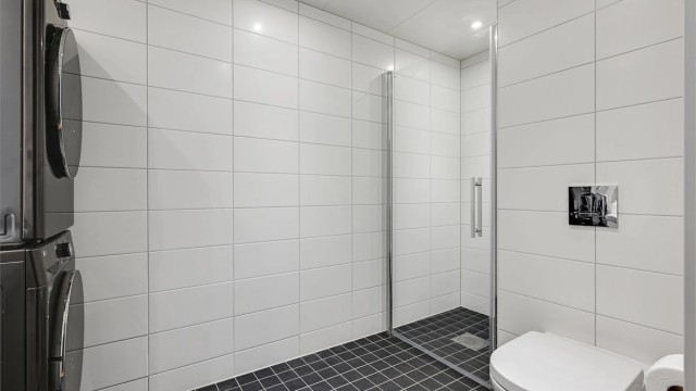 Badet er moderne innredet med heldekkende servant, vegghengt toalett, dusjnisje med glassvegger og opplegg for vaskemaskin.
