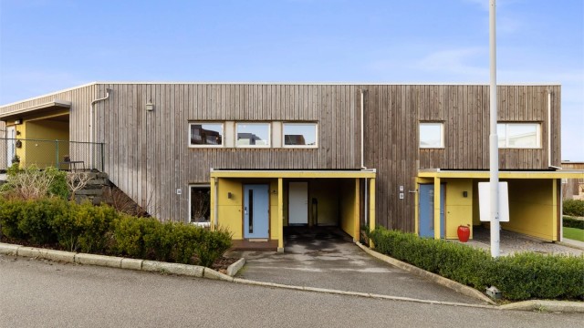 Den sentrale beliggenheten gir huset både oversikt og lune uteplasser, mens gårdsplassen foran er asfaltert og parkering i carport.