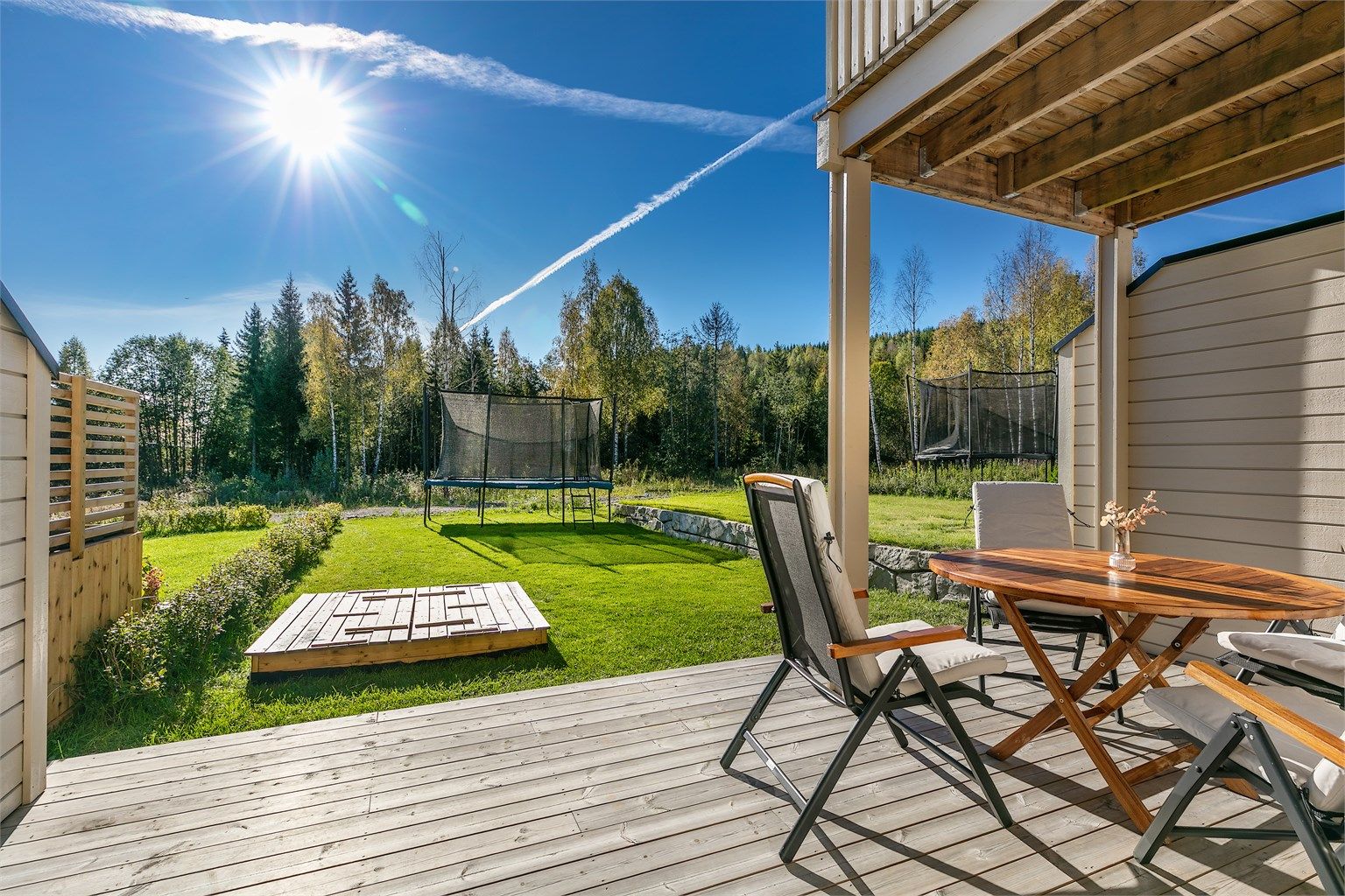Delvis overbygd uteplass med levegger som skjermer mot innsyn.