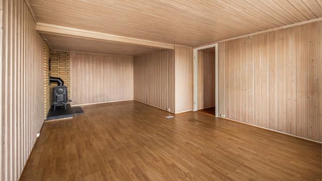 Kjellerstuen er kledd med trepanel og har en klassisk vedovn på teglsteinsmur.