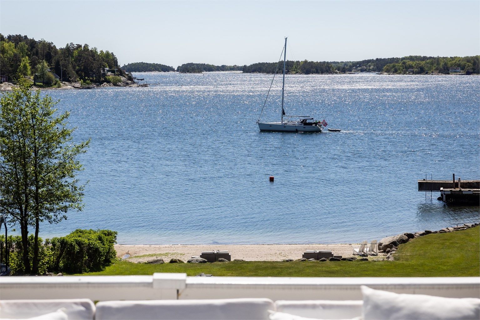 Utsikt fra terrassen mot den private stranden og bryggen.