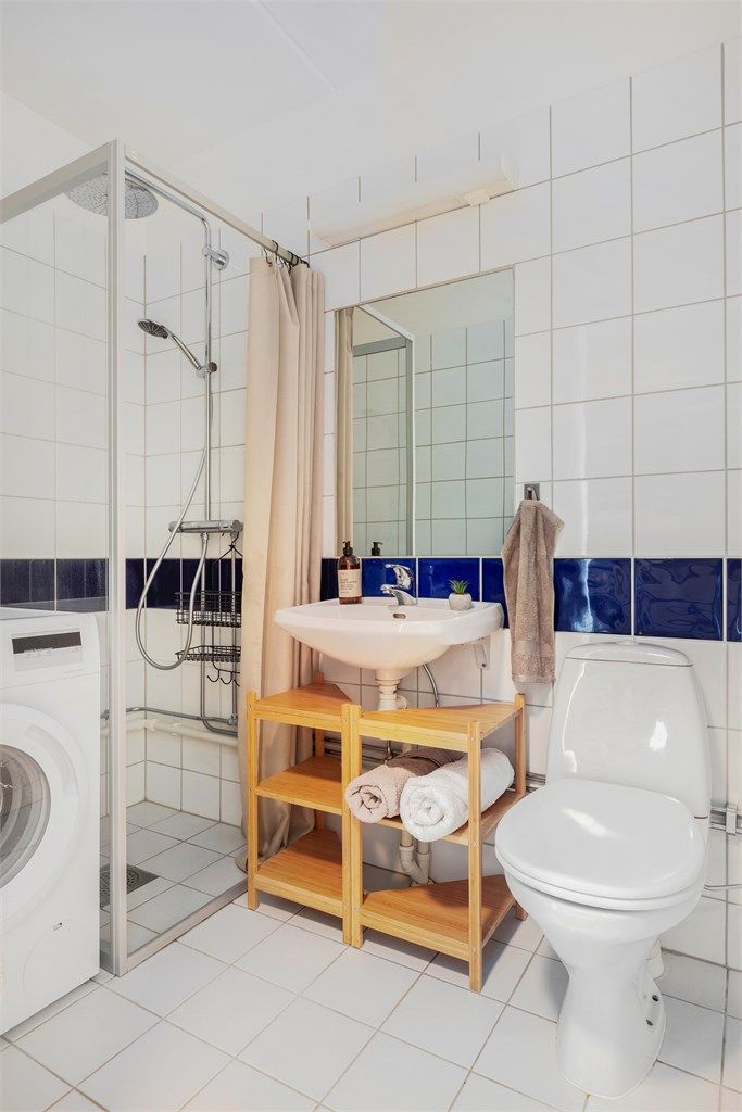 Badet er innredet med dusjnisje med glassdør, servant og toalett.