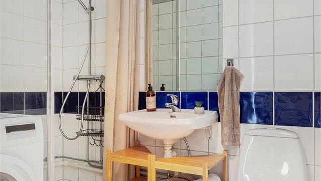 Badet er innredet med dusjnisje med glassdør, servant og toalett.