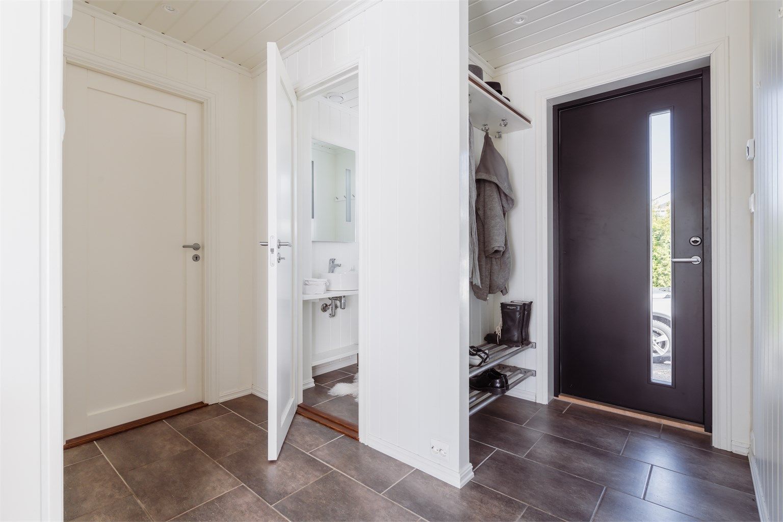 Entréen har en ny ytterdør fra 2017 og flislagt gulv med varmekabler. Herfra er det tilgang til et praktisk gjestetoalett.