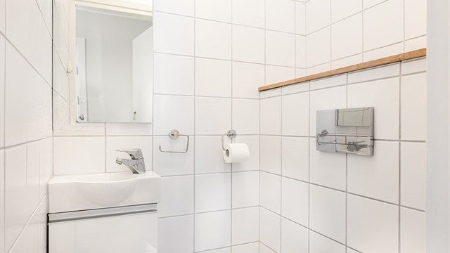 Gjestetoalettet har praktisk plassering i tilknytning til entréen. Toalettrommet har vegghengt innredning med heldekkende servant og vegghengt toalett med innebygget sisterne.