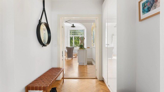 Entréen har en tofløyet dør med brann- og lydklassifisering, og parkettgulv som strekker seg videre inn i boligen.