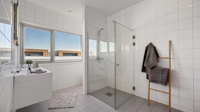 Badet er helfliset og har elektrisk gulvvarme for økt komfort. Baderomsinnredningen fra Aubo har en vegghengt servant med skuffer.