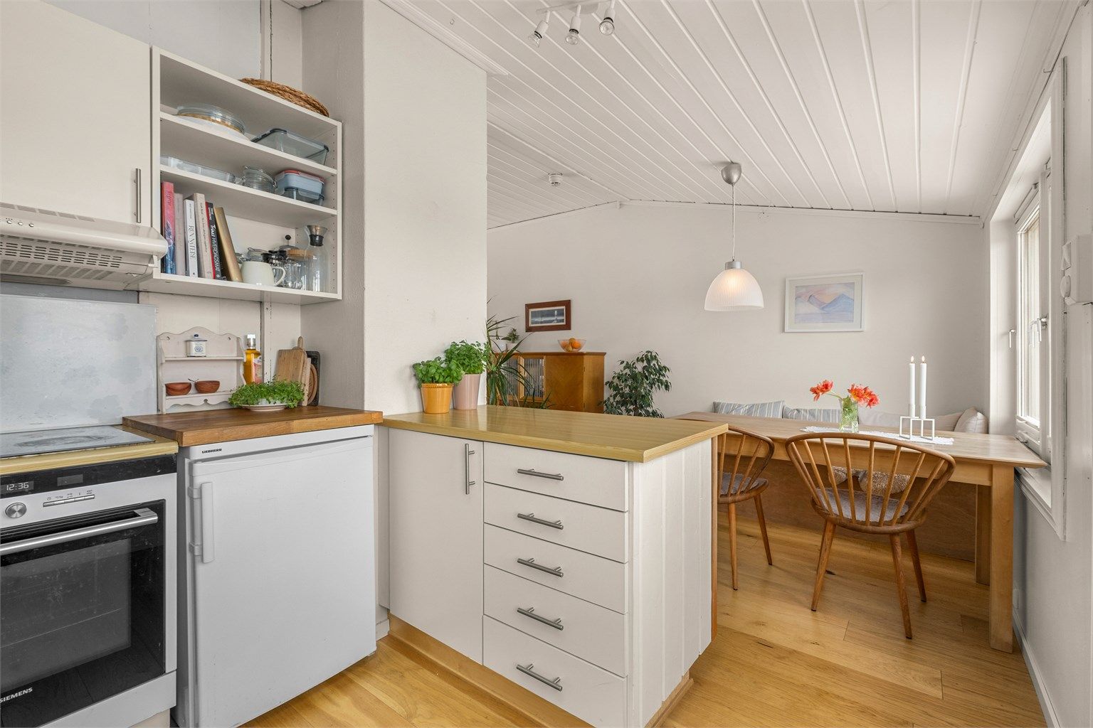 Kjøkkenet ligger naturlig tilbaketrukket fra stuen og er innredet med lyse slette flater og benkeplate med laminert overflate. 