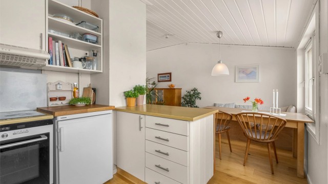 Kjøkkenet ligger naturlig tilbaketrukket fra stuen og er innredet med lyse slette flater og benkeplate med laminert overflate.