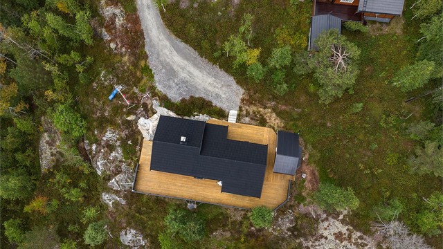 Hyttetomten ligger usjenert til i terrenget med terrassedekke rundt hytten.