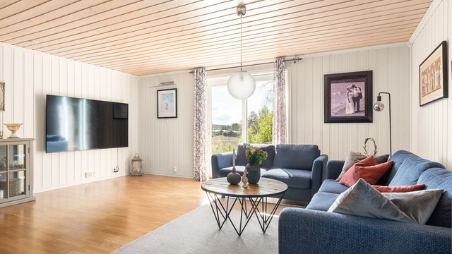 Skyve-/hevedør mot sør slipper solen inn til stuen og gir utsikt til det bølgende åkerlandskapet.