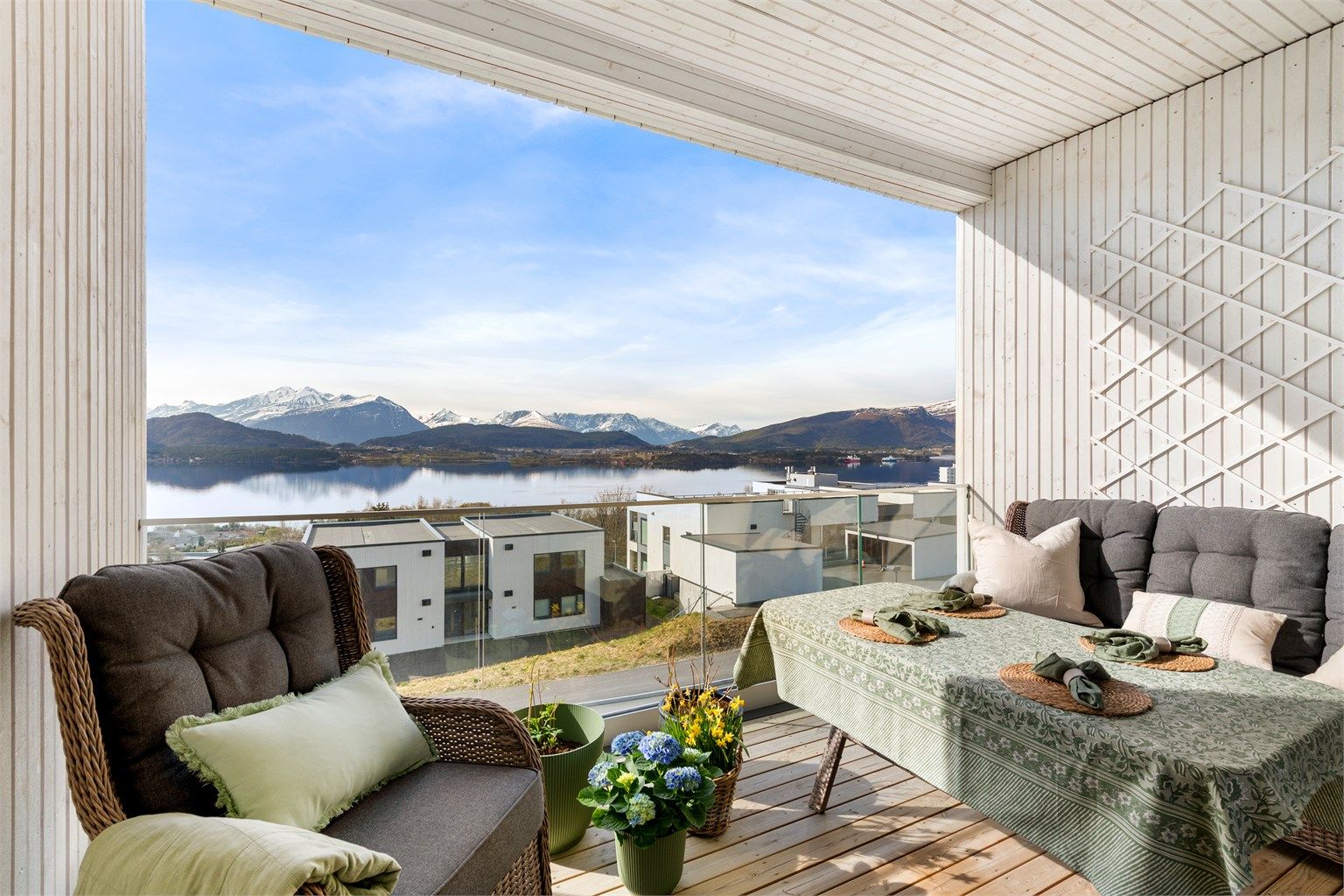 Balkongen har terrassebord på gulvet, rekkverk i glass og metall, samt utelys og stikkontakt