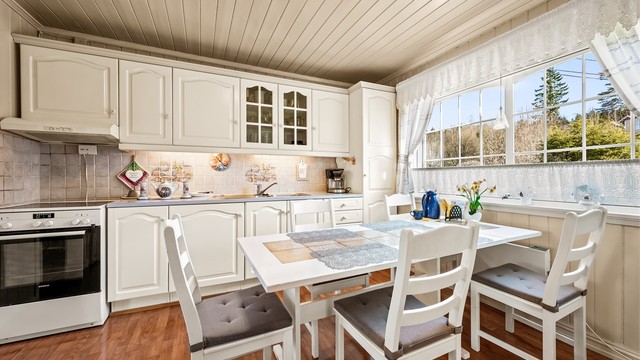 Kjøkkeninnredning fra 1989 med profilerte fronter, laminatbenkeplate og fliser over benken.