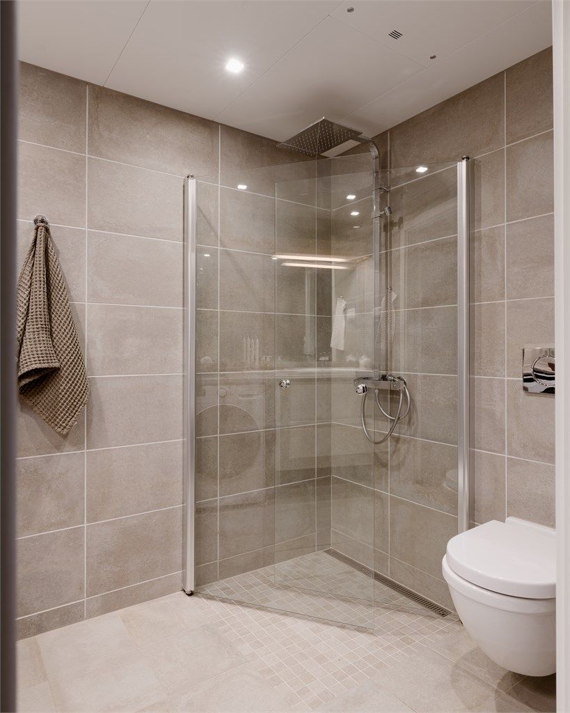 Dusjhjørne med innfellbare glassdører og dusjarmatur med både hånddusj og regndusj.