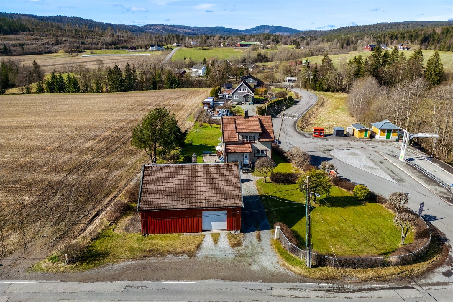 Gruset gårdsplass med god plass til parkering foran både boligen og uthuset.