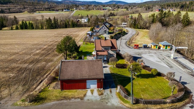 Gruset gårdsplass med god plass til parkering foran både boligen og uthuset.