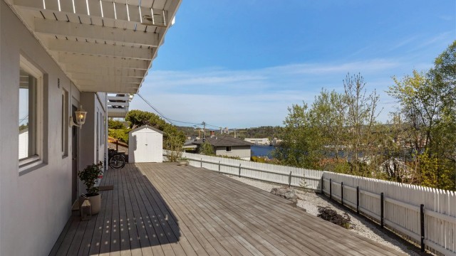 Terrasse ved inngangsparti med enkelt redskapshus rett frem.