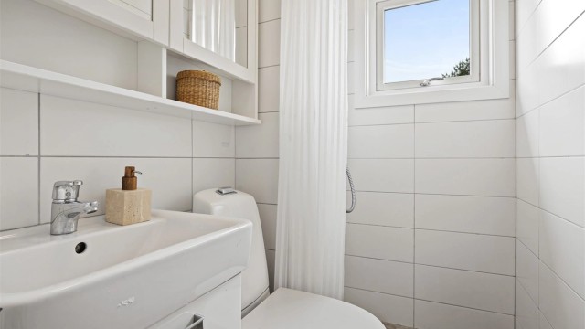 Badet har dusjhjørne med veggmontert regnfallsdusj og opplegg for dusjforheng.