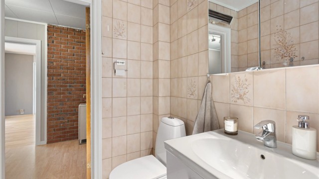 Badet er utstyrt med gulvstående toalett og speilskap med belysning.