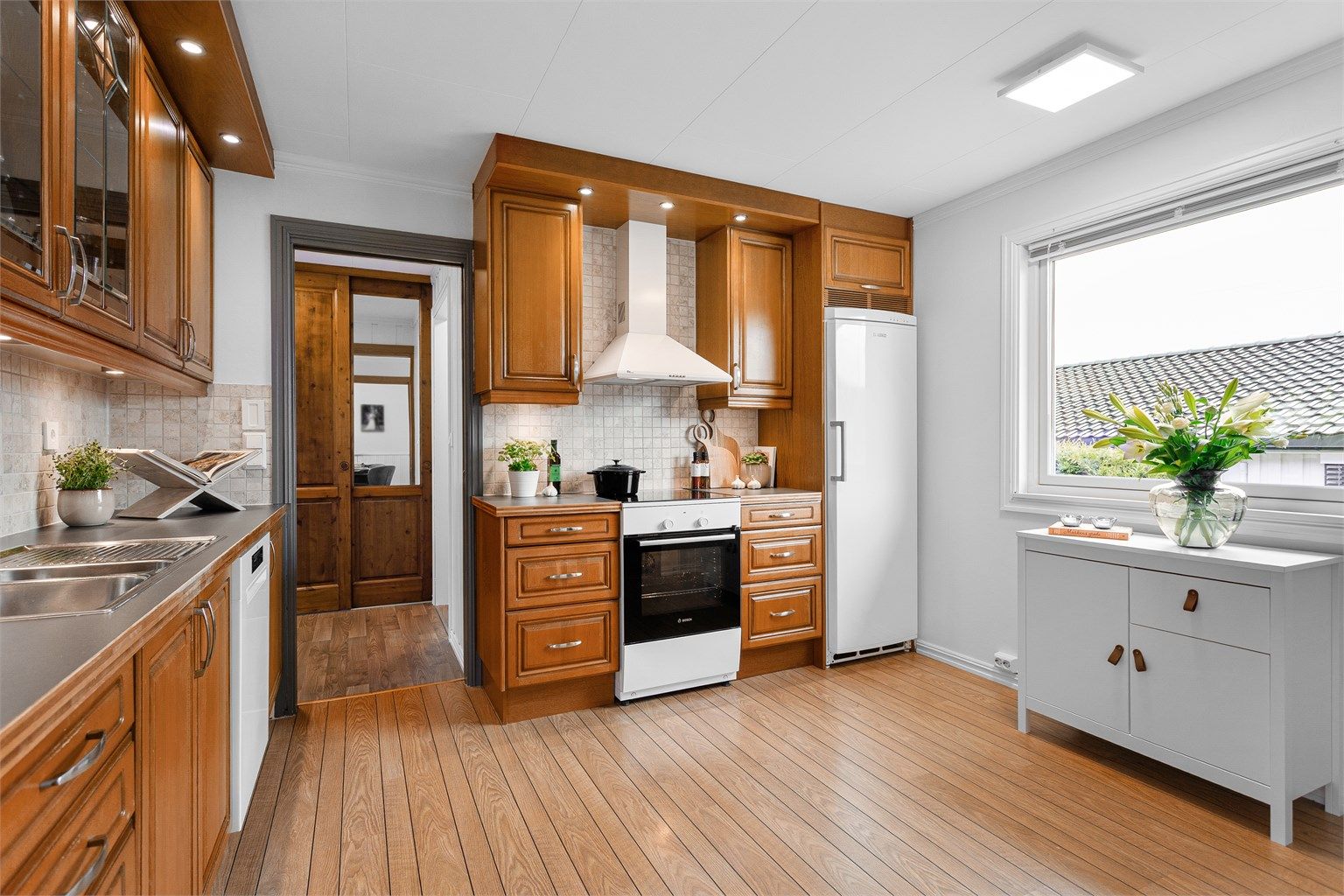 Komfyr med induksjonsplatetopp fra 2025.  Oppvaskmaskin under benkeplate fra 2025. Veggmontert ventilator.  Kjøleskap i nisje. Hvitevarer på kjøkkenet medfølger eiendommen.