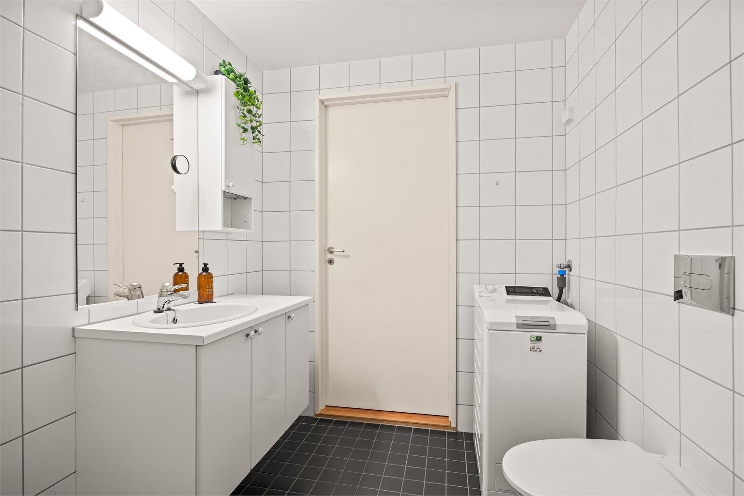 Flislagt bad med gulvvarme og opplegg for vaskemaskin.