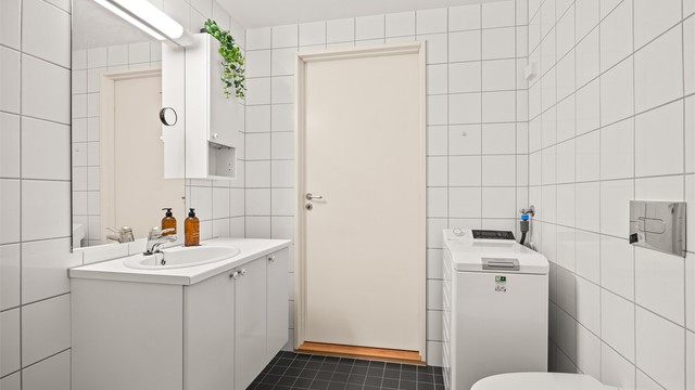 Flislagt bad med gulvvarme og opplegg for vaskemaskin.