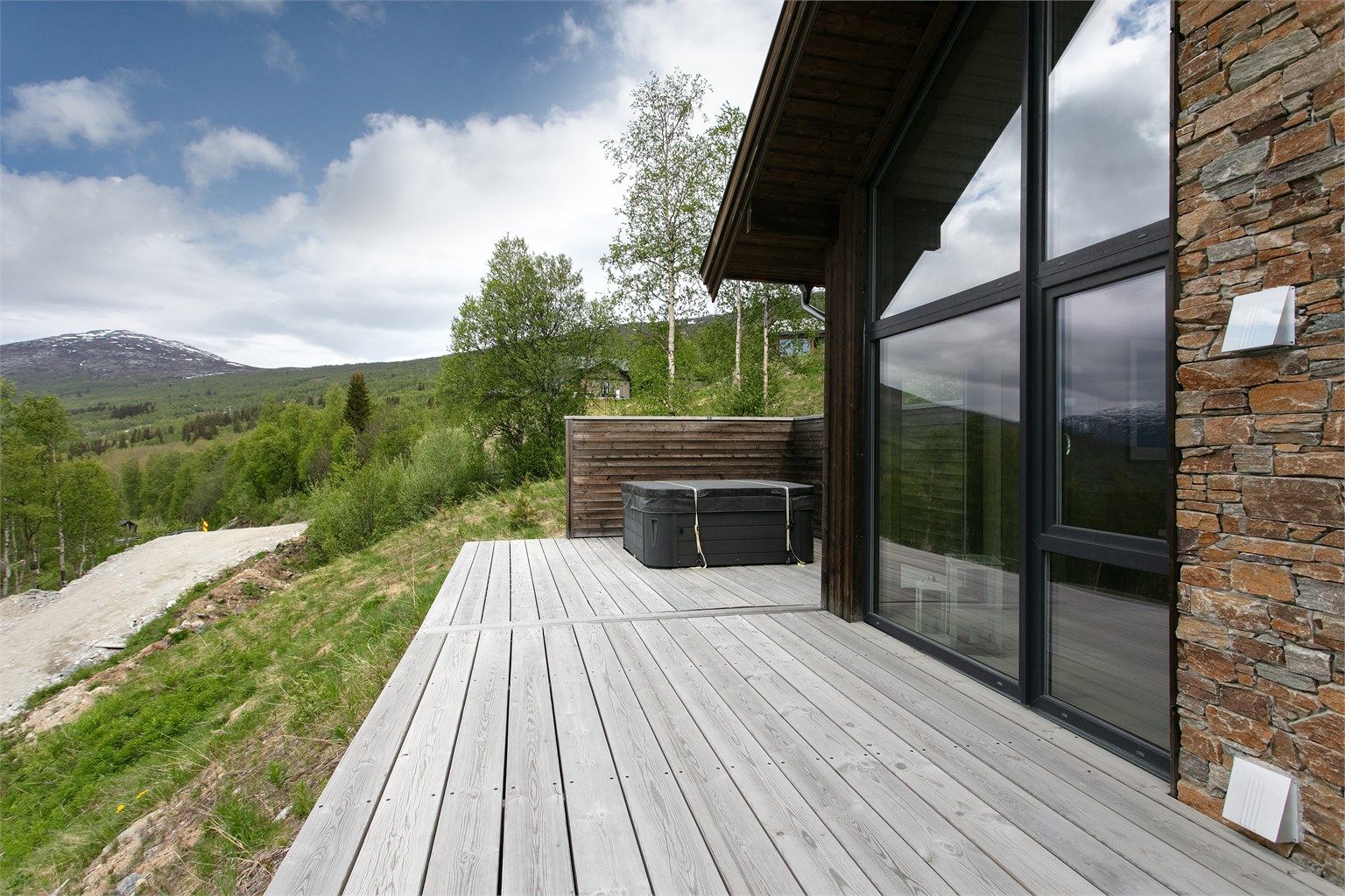 Jacuzzien er plassert avskjermet bak leveggen med utsikt mot fjellheimen.