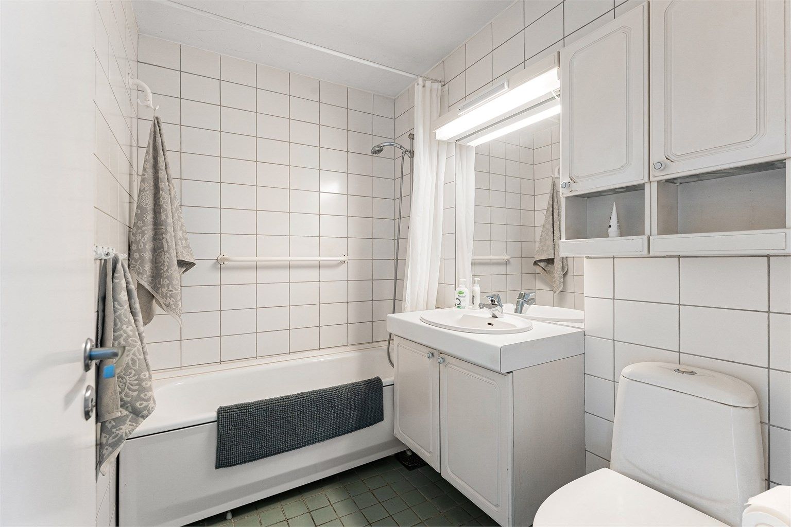 Badet i hovedetasjen er fra byggeåret, med flislagt gulv med gulvvarme og badekar.
