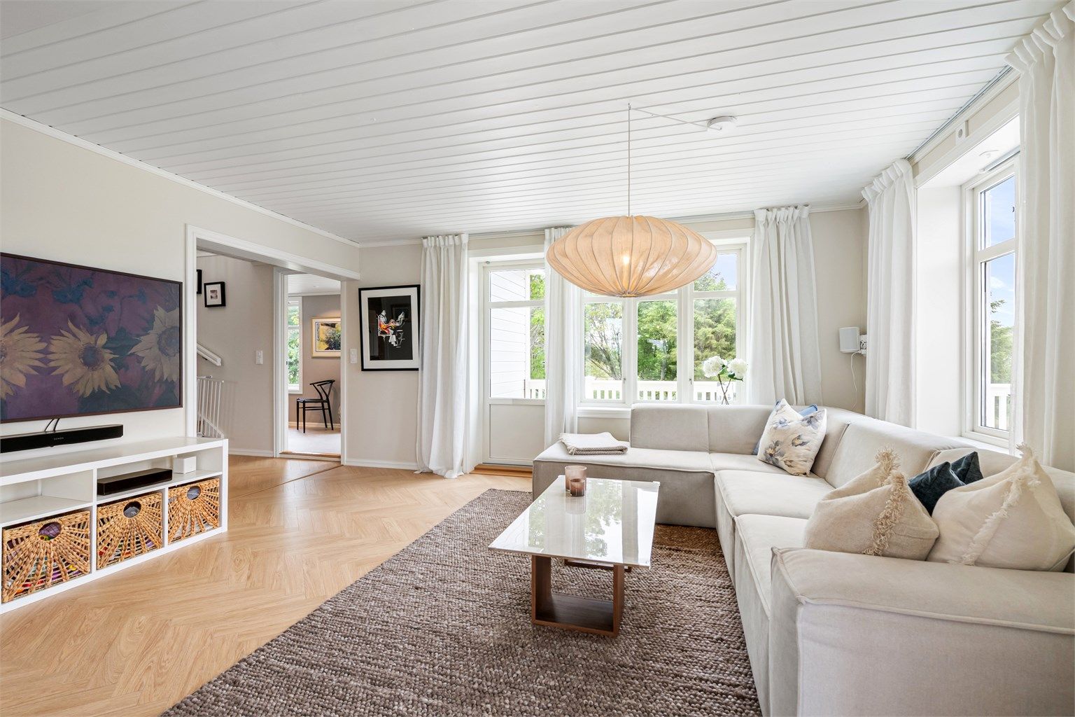 Gjennomgående parkettgulv fra 2023 og panelbord i himling i boligens oppholdsrom.