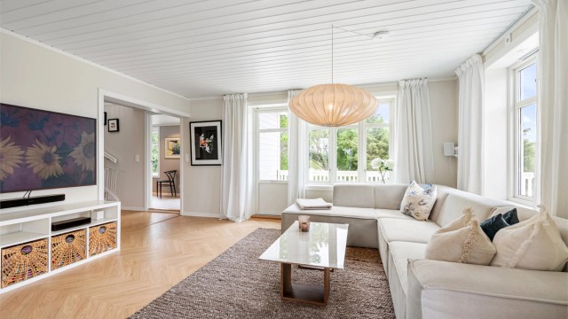 Gjennomgående parkettgulv fra 2023 og panelbord i himling i boligens oppholdsrom.